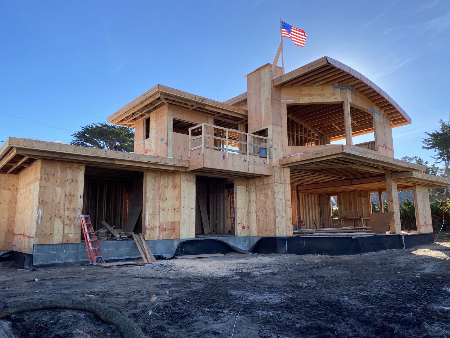 Full front elevation of the Pebble Beach custom home during structural framing